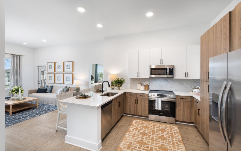 kitchen with stainless appliances, two tone cabinets, bar stools